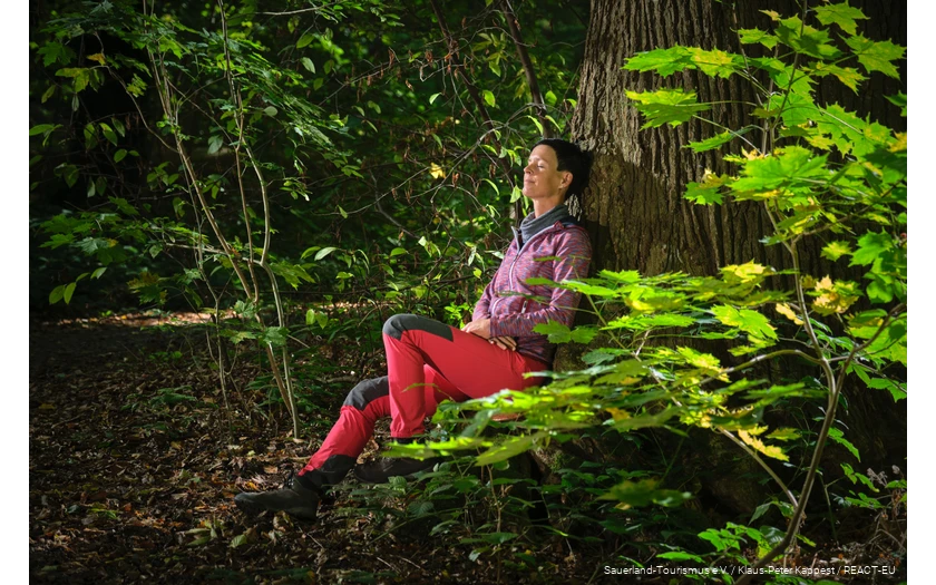 A woman enjoys nature while bathing in the forest.