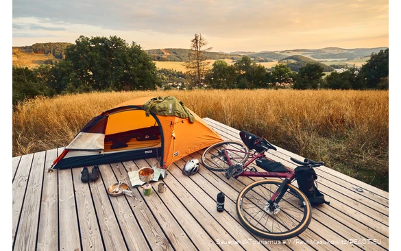 Gravelbike und Zelt auf einer Trekkingplattform mit Blick über die Landschaft des Sauerlandes