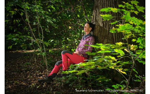 A woman enjoys nature while bathing in the forest.