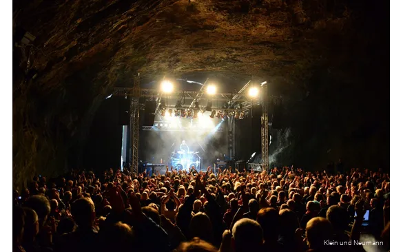 Konzert in der Dechenhöhle mit einer Menge Besucher, die der Musik auf der Bühne lauschen.