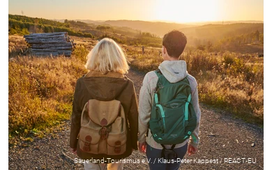 Twee vrouwelijke wandelaars op de Sauerland-Waldroute bij zonsondergang.