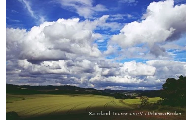 Dicke Wolken am blauen Himmel ziehen über die Sauerländer Landschaft.