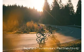 Zwei Rennradfahrer bei Sonnenaufgang auf einer Sepentine