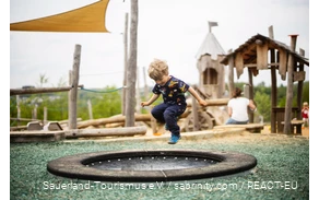Boy jumping on a trampoline, a playground in the background
