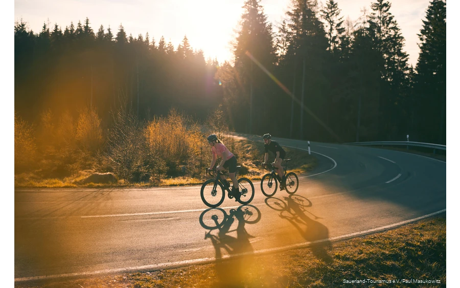 Two racing cyclists at sunrise on a sepentine