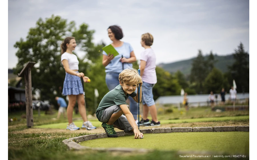 Eine Familie beim Minigolfen am Diemelsee. Ein Sohn bereitet seinen nächsten Schlag vor.