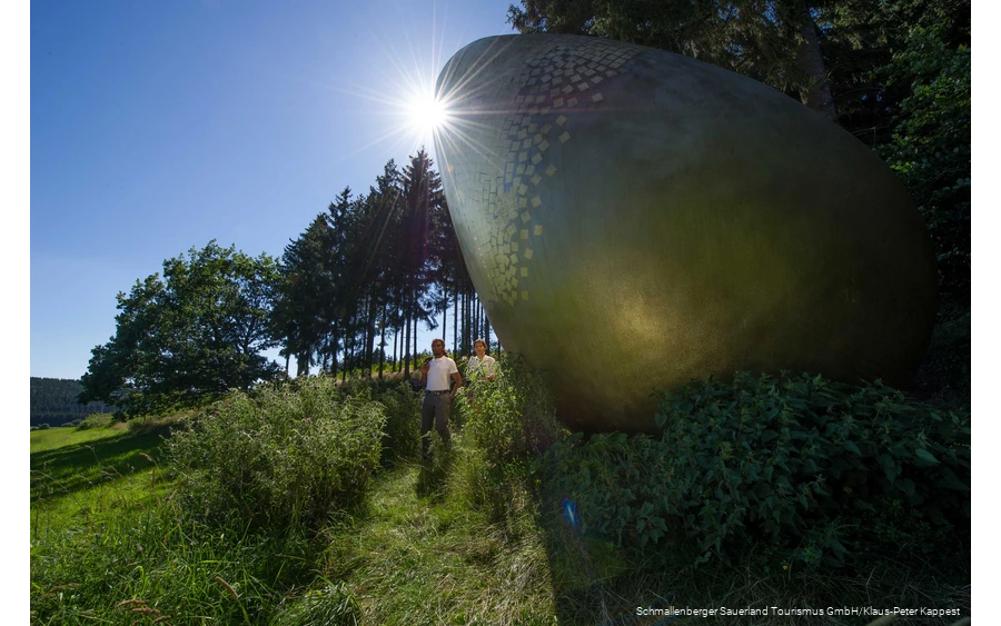 Two hikers at the "golden egg" on the Forest Sculpture Trail.