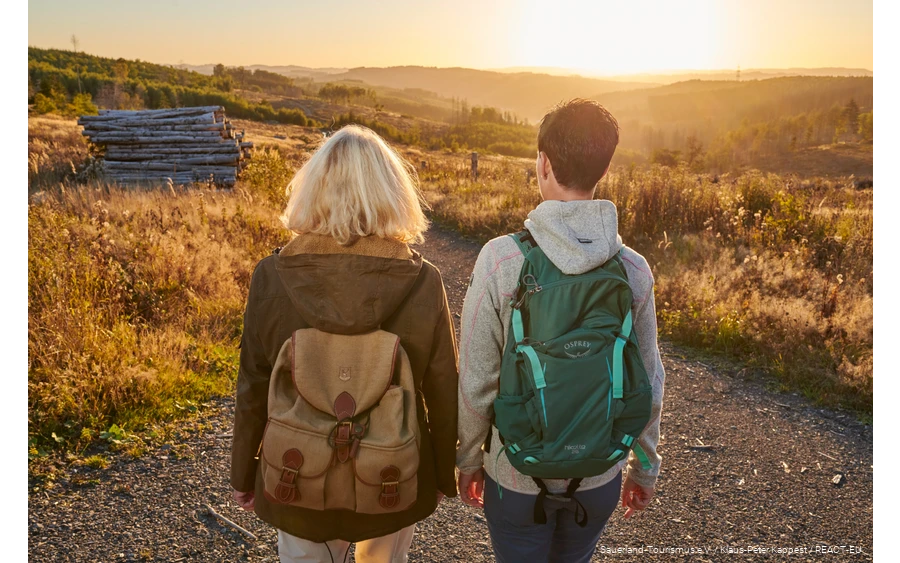 Twee vrouwelijke wandelaars op de Sauerland-Waldroute bij zonsondergang.