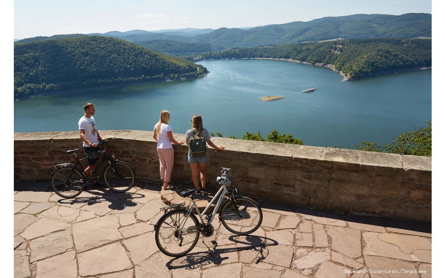 Dei Radfahrer blicken auf den Edersee