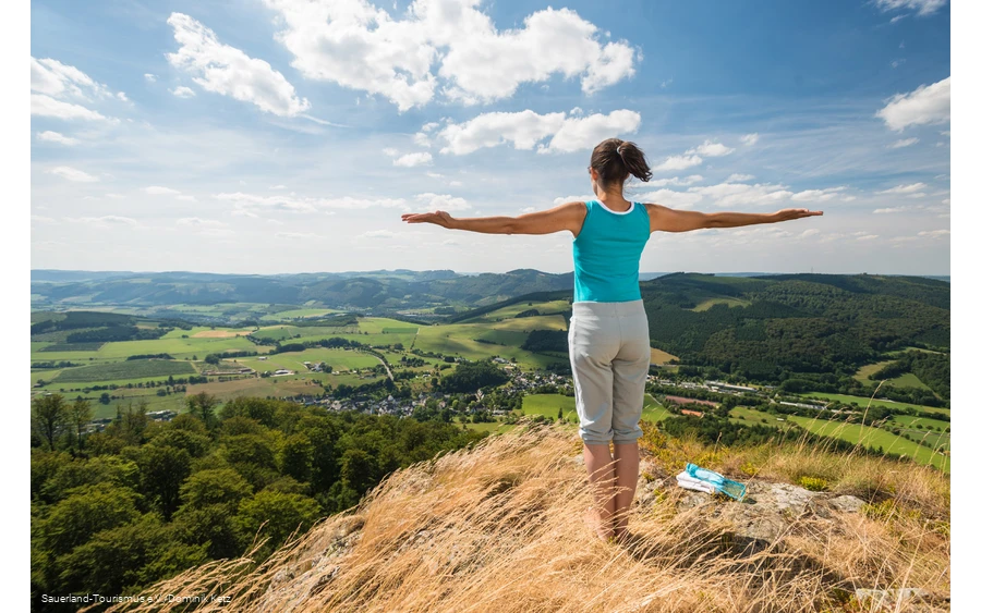 Eine Frau genießt die weite Aussicht auf den Bruchhauser Steinen