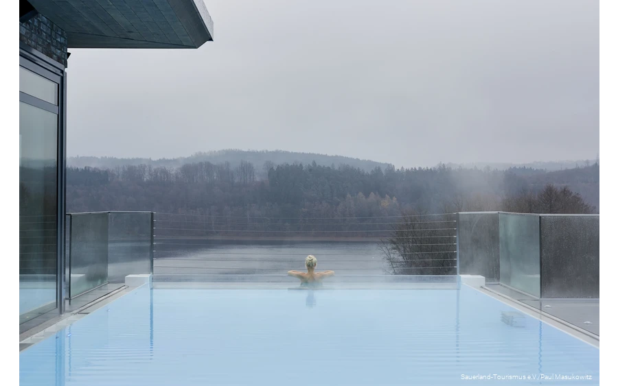 A woman relaxes in the infinity pool of a hotel.
