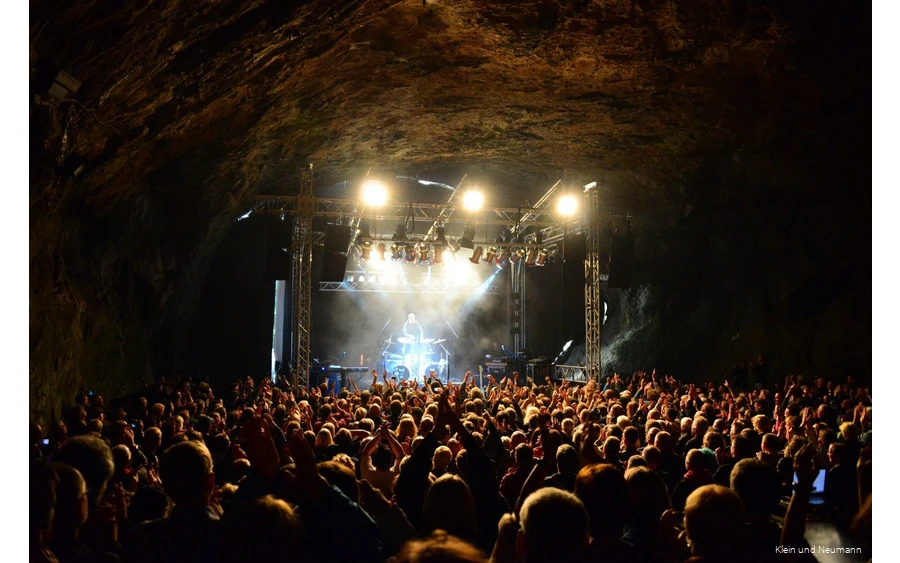 Concert in de Dechenhöhle met veel bezoekers die naar de muziek op het podium luisteren.