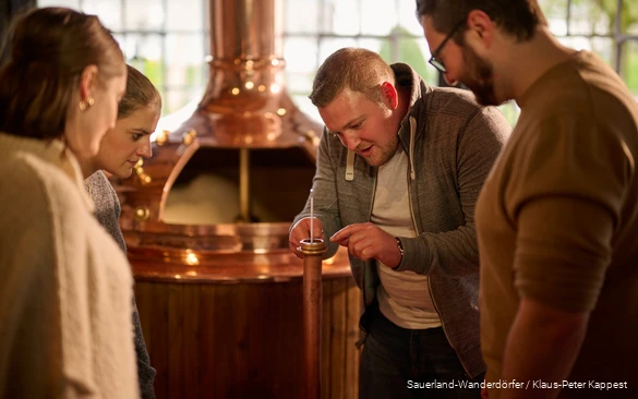 One group stands in front of a brewing kettle and is given an explanation of part of the brewing process.