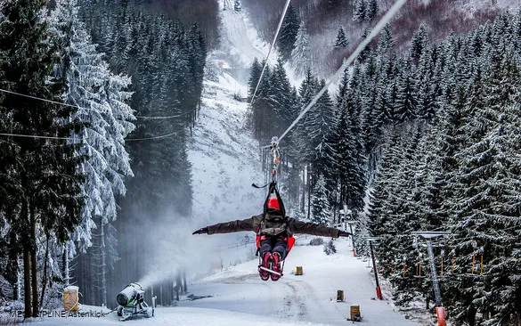 Ein Mann stürzt sich an der Megazipline hinab ins Tal.