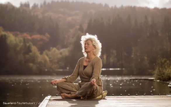 Een vrouw ontspant met yoga-oefeningen bij een meer.