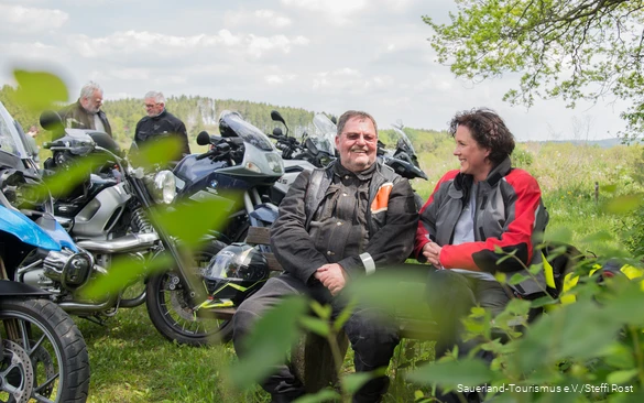 Motorcyclists take a break on a bench in the Sauerland.