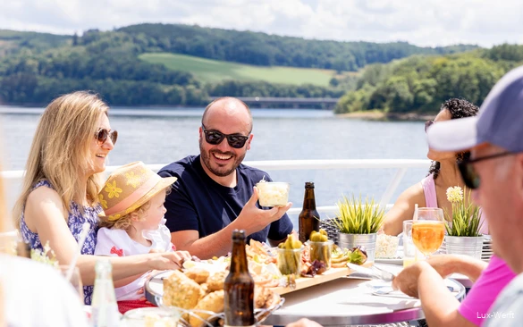 Eine Familie an Deck eines Schiffs im Sommer, die frühstückt