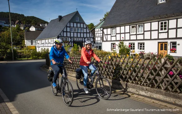 Een stel maakt een fietstocht door een vakwerkdorp.
