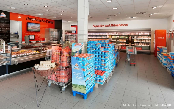 Einblick in den Verkaufsraum des Werksverkaufs mit vielen Wurstdosen und einer Frischetheke