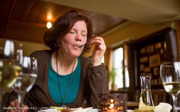 Een vrouw geniet van haar Essen maaltijd in een herberg in Sauerland.