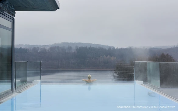A woman relaxes in the infinity pool of a hotel.