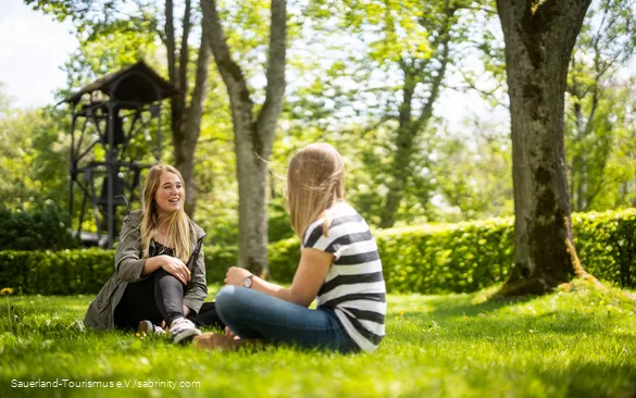 Two friends are sitting on the grass and chatting.