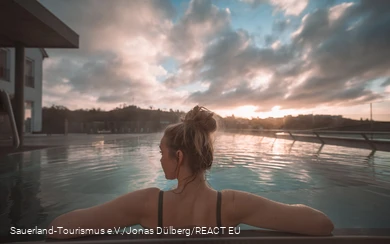 Eine Frau von hinten fotografiert genießt den Pool beim Sonnenaufgang