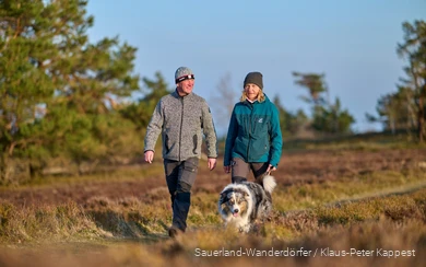 Een stel wandelt in de winter met hun hond over de Kahle Pön. De winterzon schijnt zachtjes.