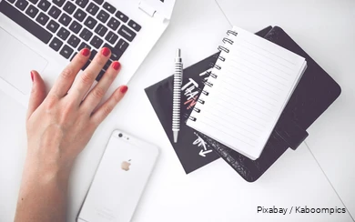 Een bureau met laptop, smartphone en notitieblok.