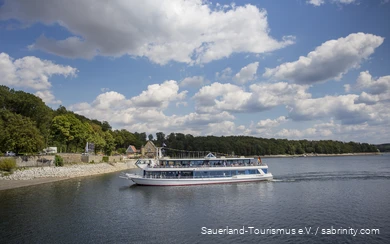 Der Möhnesee an einem Sommertag mit einem Personenschiff voller Menschen im Zentrum