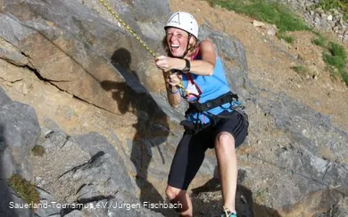 Frau klettert am Felsen.