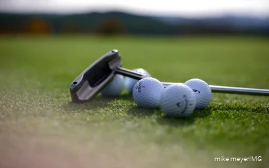 Golfschläger und Golfbälle liegen auf dem Platz.