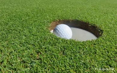 Een golfbal ligt in de hole.