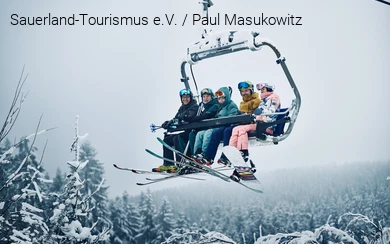 A cheerful group of winter sports enthusiasts is sitting in the chairlift.