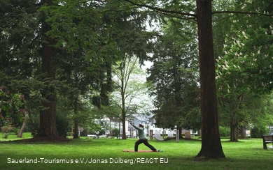Eine Frau macht Pilatesübungen im Kurpark in Olsberg