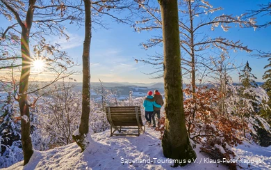 Een stel geniet van de winterzon in de sneeuw.