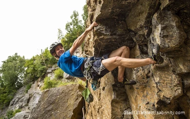 Ein junger Kletterer hängt in der Felswand.