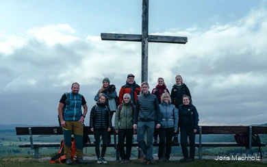 Die Teilnehmer des InstaHikes stehen vor dem Gipfelkreuz Usselner Kreuz. Der Himmel ist wolkenbehangen.