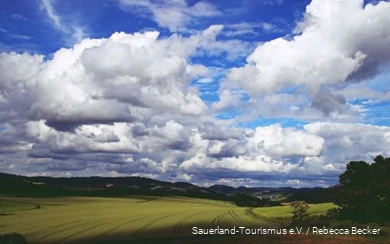 Thick clouds in the blue sky drift across the Sauerland landscape.