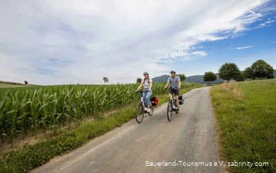 Een stel fietst rustig over een fietspad door groene weiden.