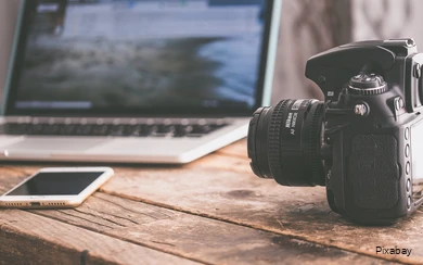 View of a table with laptop, smartphone and SLR camera.