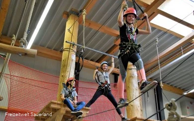 Kinderen klimmen in het indoor hoge touwenparcours.