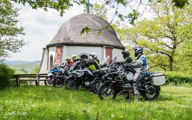 Motorrijders nemen een pauze bij de kapel boven Braunshausen.