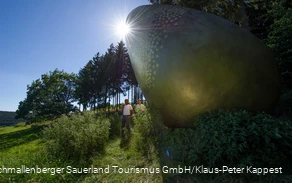 Twee wandelaars bij het "gouden ei" op het Forest Sculpture Trail.
