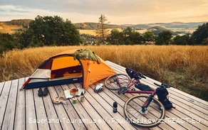 Gravel bike and tent on a trekking platform with a view over the Sauerland landscape