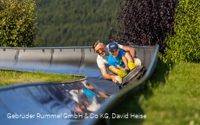 Mann und Junge auf der Sommerrodelbahn