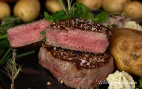 Nahaufnahme eines Tellers mit einem Steak, Kartoffeln und Kräuterbutter