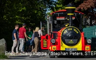 Einige Personen steigen in eine rot-gelbe Eisenbahn ein.