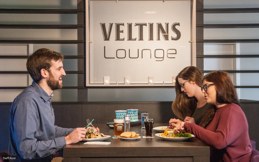 Eine Gruppe isst in der Veltins Lounge des Oversusms in Winterberg.