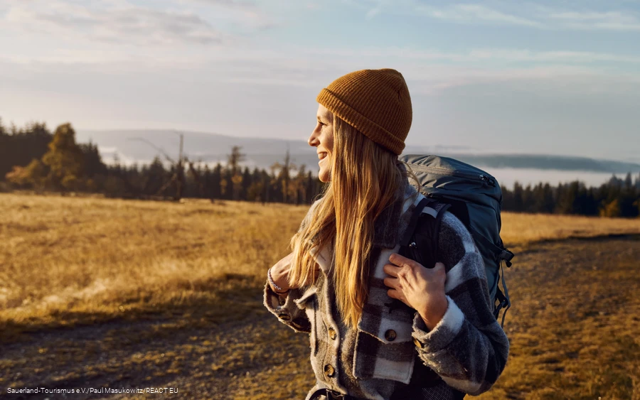 A woman in a cap enjoys the sunrise on the Kahler Asten and gazes into the distance